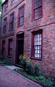 Facade of a brick building with an windows and yellow flowers in the foreground