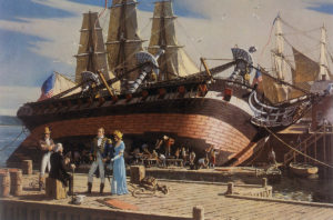 Large ship on its side, people in foreground, ship is being covered in sheets of copper